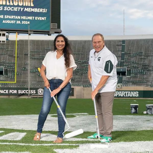 two volunteers helping paint the field