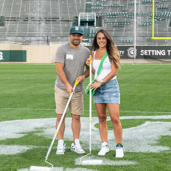 two volunteers helping paint the field