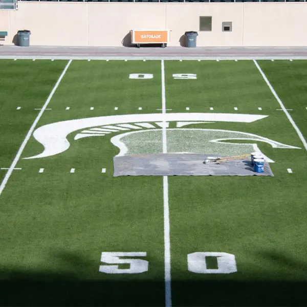paint buckets on the field with rollers next to helmet logo