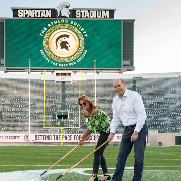 two volunteers helping paint the field