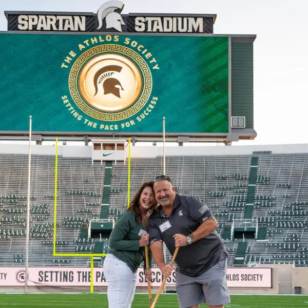 two volunteers helping paint the field