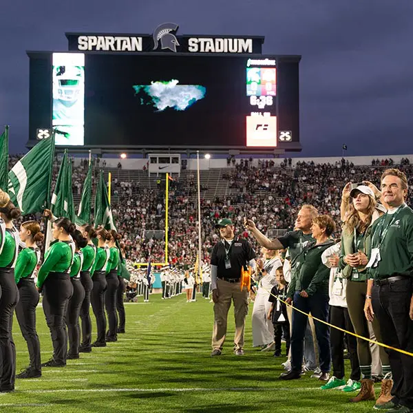 Fans on the field behind the flag squad