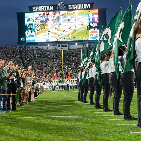 Fans on the field behind the flag squad