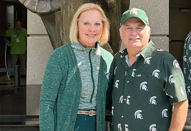 Nancy and Gary Mattson posing in front of spartan statue